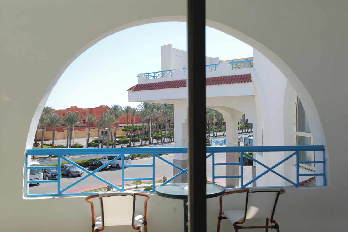 A balcony with a view of a parking lot and buildings.