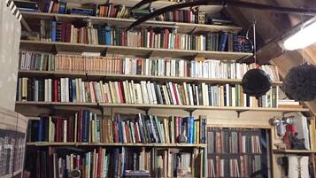 Ein mehrgeschossiges Bücherregal aus Holz, gefüllt mit Büchern, in einem Raum mit schrägen Holzbalkendecken.