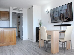 Enjoy a spacious living area with a dining table, TV, and kitchenette, perfect for relaxing and preparing meals.