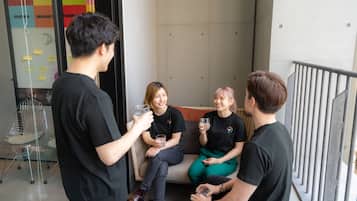 A group of people sitting on a bench in a modern indoor space with a glass partition and a metal railing.