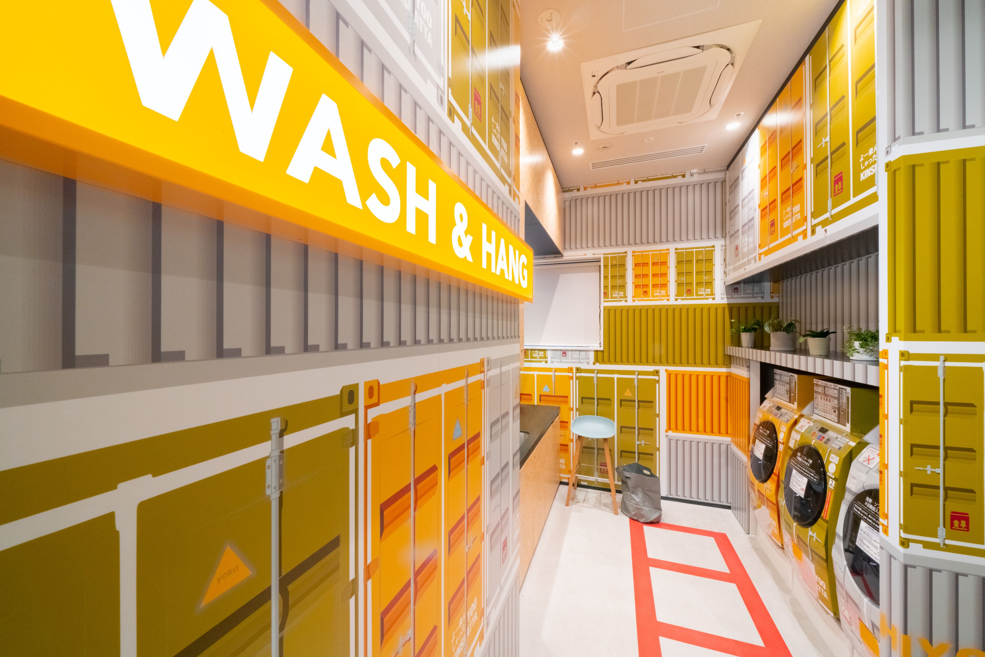 Un intérieur moderne et lumineux, agrémenté d’une enseigne jaune bien visible sur laquelle on peut lire : « LAVAGE ET SÉCHAGE ».
