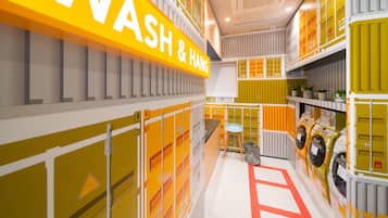 A brightly lit, modern interior with a prominent yellow sign reading "WASH & HANG".