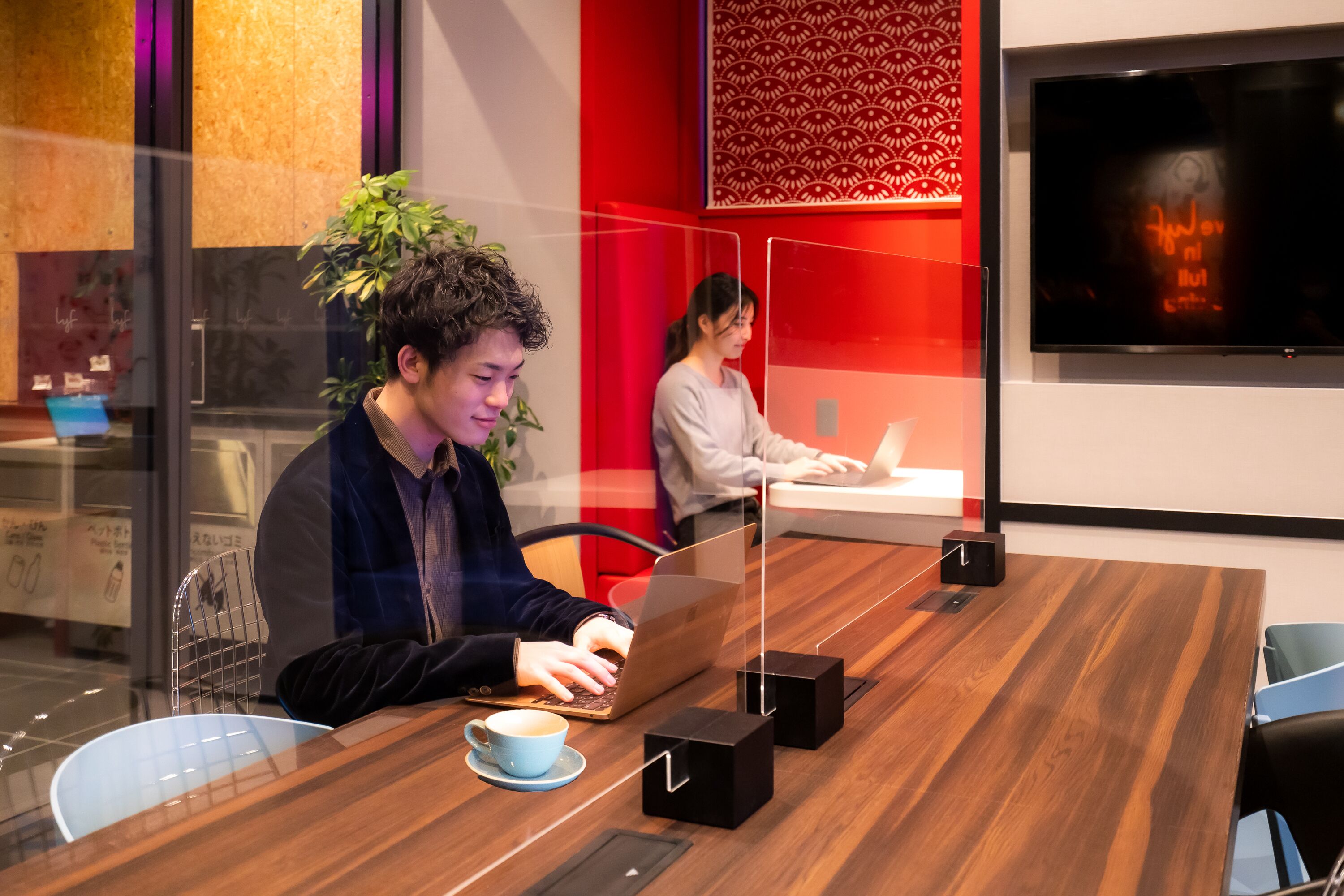 Uma sala de conferências moderna com uma mesa de madeira, laptops e uma tela de TV.