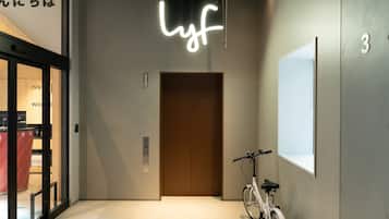 A modern elevator with a neon sign, a bicycle, and a number '3' on the wall.