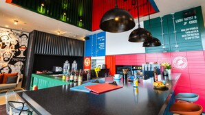 Un espace bar moderne avec un comptoir noir, des touches de rouge et de vert, et un luminaire suspendu.