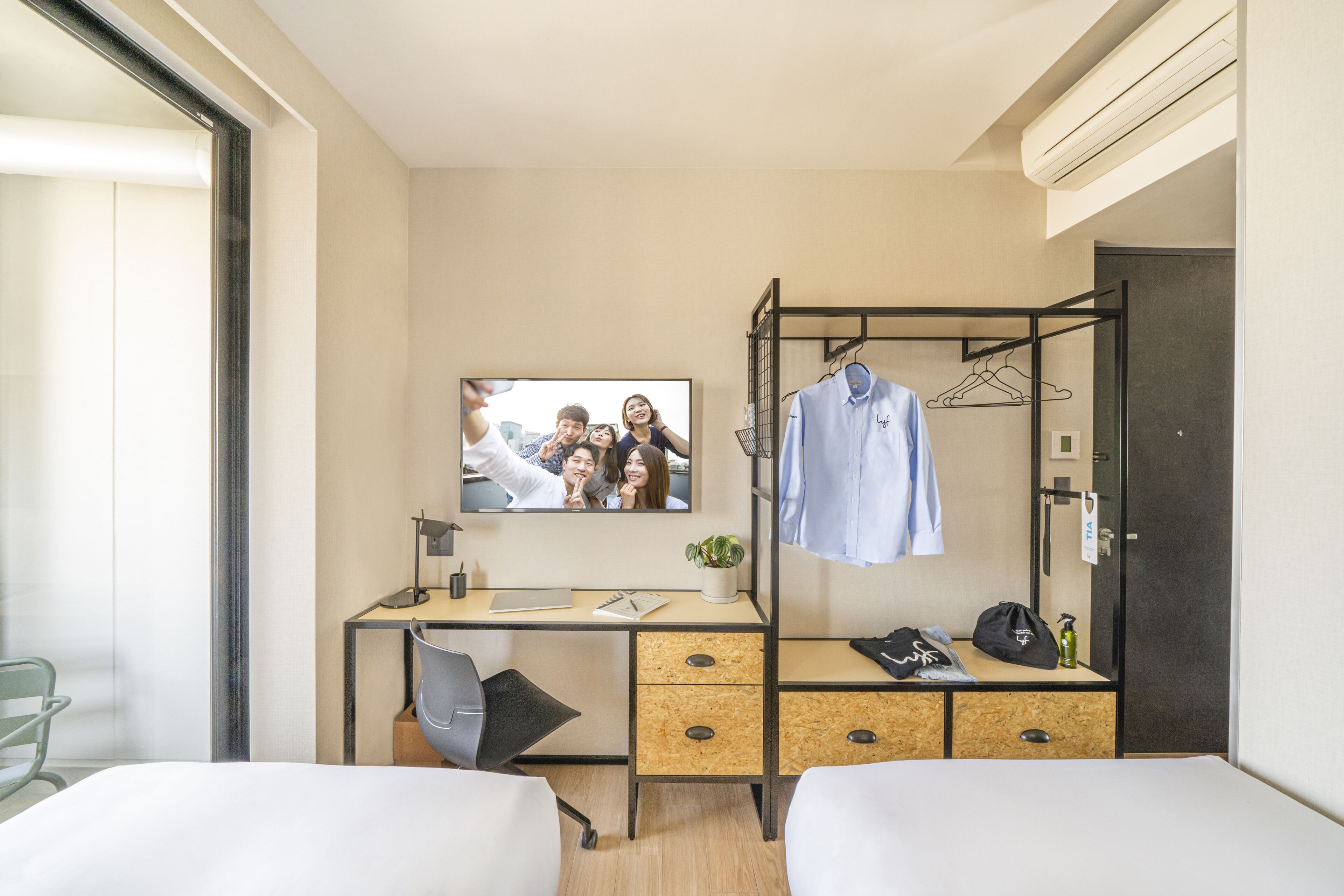 A hotel room with a bed, a desk with a computer, a TV, and a wardrobe.