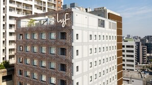 Un bâtiment moderne doté d’une façade originale, caractérisée par une structure en treillis et un panneau « lyf » bien visible.