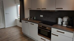 Una cocina moderna con armarios blancos, un lavabo de acero inoxidable, horno empotrado y cafetera.