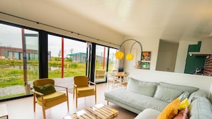 A modern living room with a large window, a sofa, two armchairs, and a coffee table. - Chic Stay Near North Sea (Callantsoog)