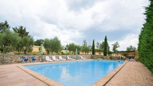Ein rechteckiger Pool mit Liegestühlen und Sonnenschirmen am Rand.