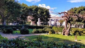 A park with a classical building, manicured lawns, and a variety of trees. - Cozy Apartment in Siracusa near Sea & City Center (Syracuse)