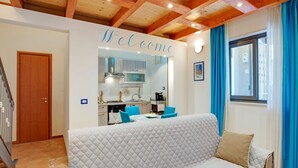 A cozy living room with a sofa, a kitchen area, and a staircase. - Cozy Apartment in Siracusa near Sea & City Center (Syracuse)