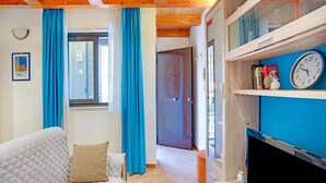 A cozy room with a wooden ceiling, a bed with a quilted cover, a blue wall, and a clock. - Cozy Apartment in Siracusa near Sea & City Center (Syracuse)