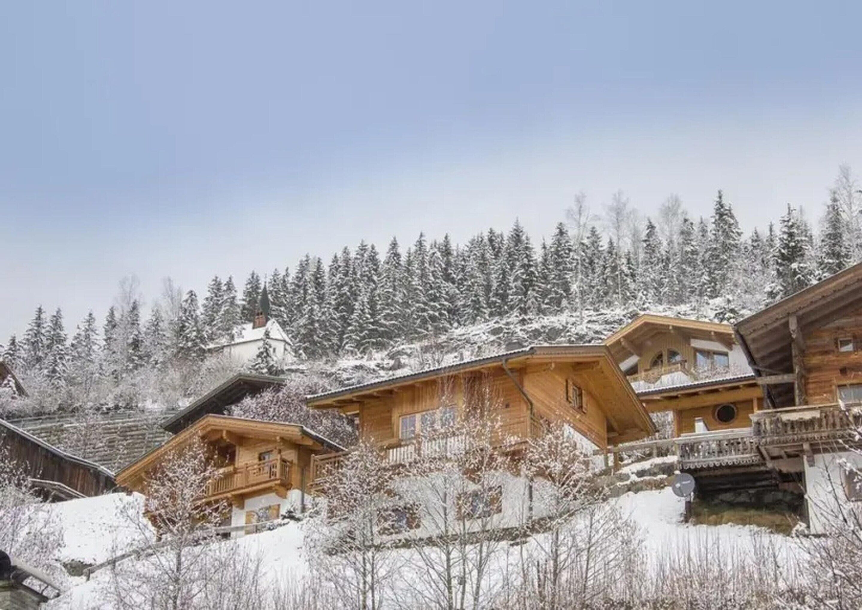Eine Holzhütte mit einem Balkon, umgeben von schneebedeckten Bäumen.