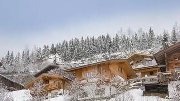 Eine Holzhütte mit einem Balkon, umgeben von schneebedeckten Bäumen.