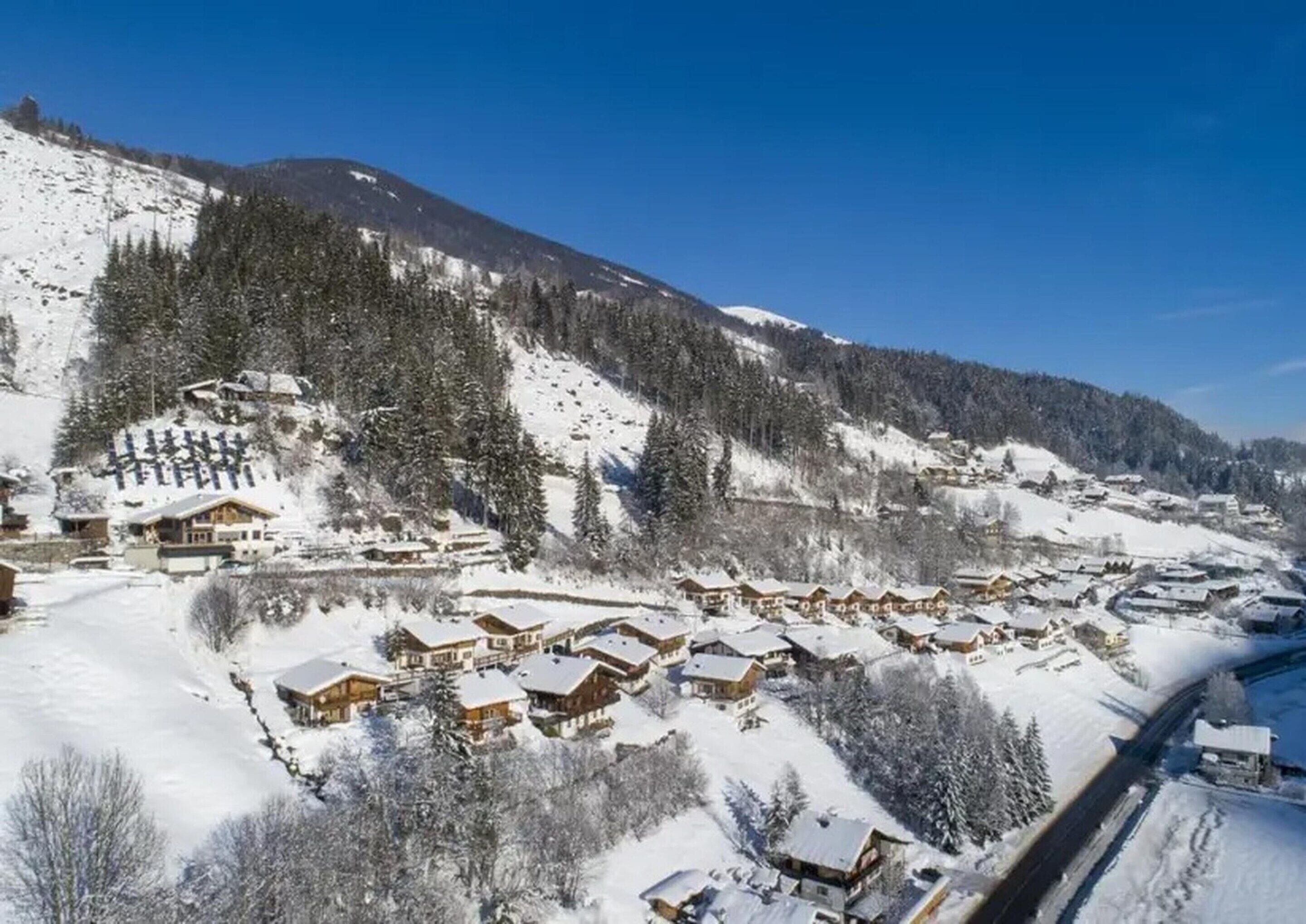 A snow-covered mountain village with wooden chalets and a ski slope.