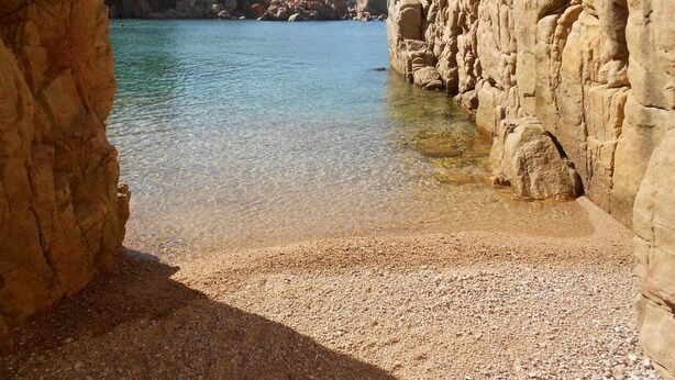 A coastal landscape with clear water, rocky formations, and a pebbly beach. - Belvilla by OYO Deligias (Trinità d'Agultu e Vignola)