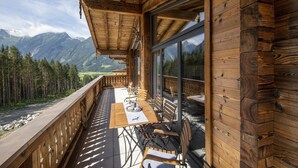 A wooden deck with a table and chairs overlooking a mountainous landscape. - Ornate Chalet in Neukirchen near Wildkogel Ski Arena (Neukirchen am Grossvenediger)