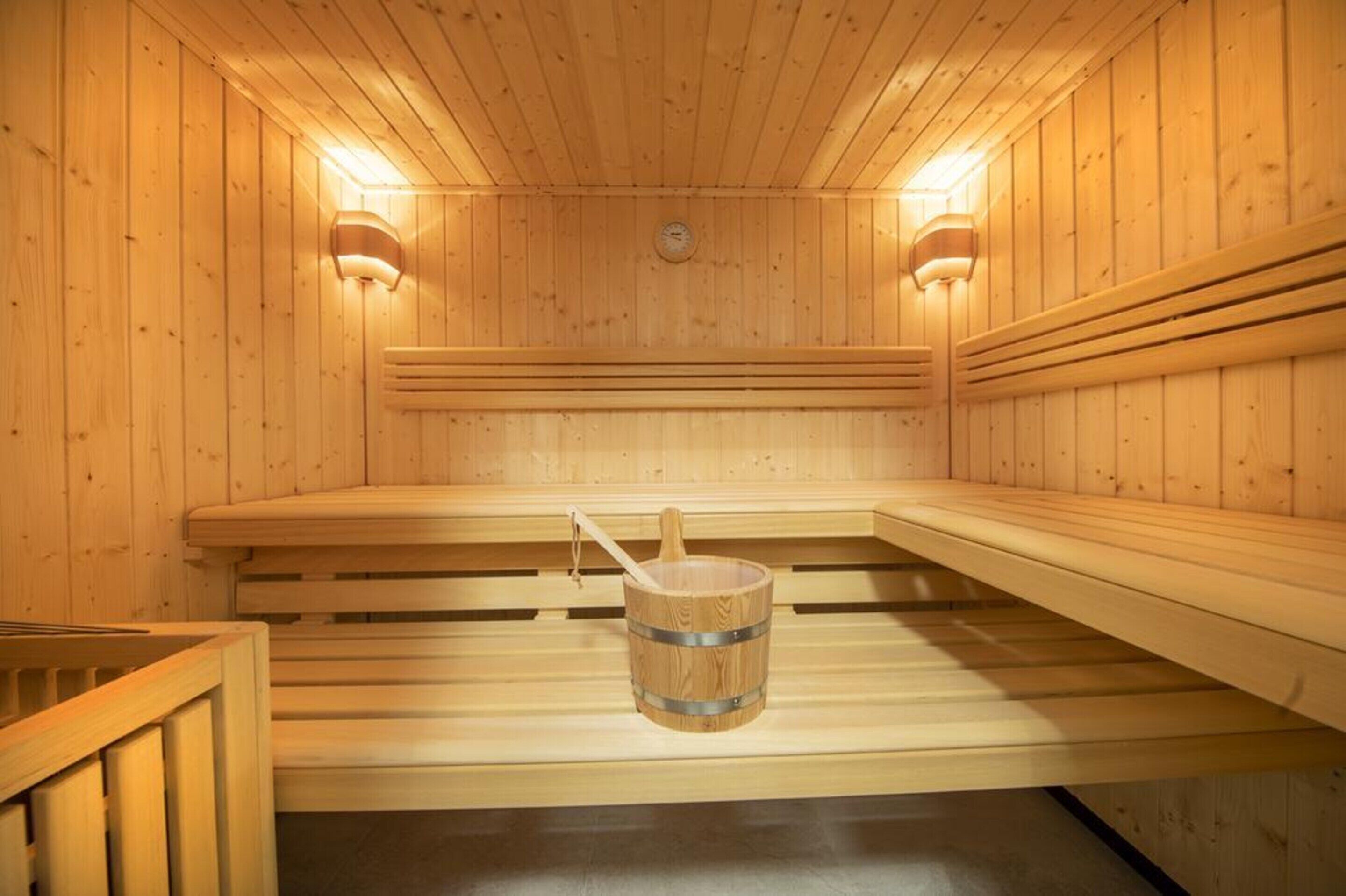 Een houten sauna met banken en een houten emmer.