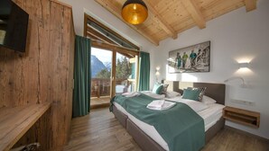 A bedroom with a wooden ceiling, a bed with green bedding, a mounted TV, and a painting on the wall. - Alpine Chalet With Ski-in Access (Neukirchen am Grossvenediger)