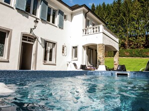 A large house with a swimming pool, outdoor seating, and a well-maintained garden.