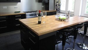 A modern kitchen with a wooden island, stainless steel appliances, and a view of greenery outside. - Luxurious Countryside Holiday Home With Garden (Malmedy)