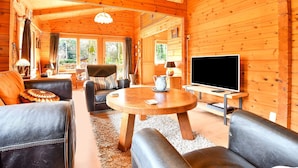 A cozy cabin interior with a wooden interior, a round wooden table, leather sofas, and a television. - Wooden Holiday Home in Meijel With Private Garden (Meijel)