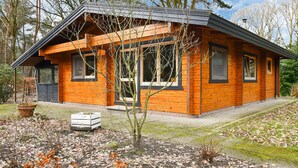 A wooden cabin with a sloped roof, large windows, and a small porch. - Wooden Holiday Home in Meijel With Private Garden (Meijel)