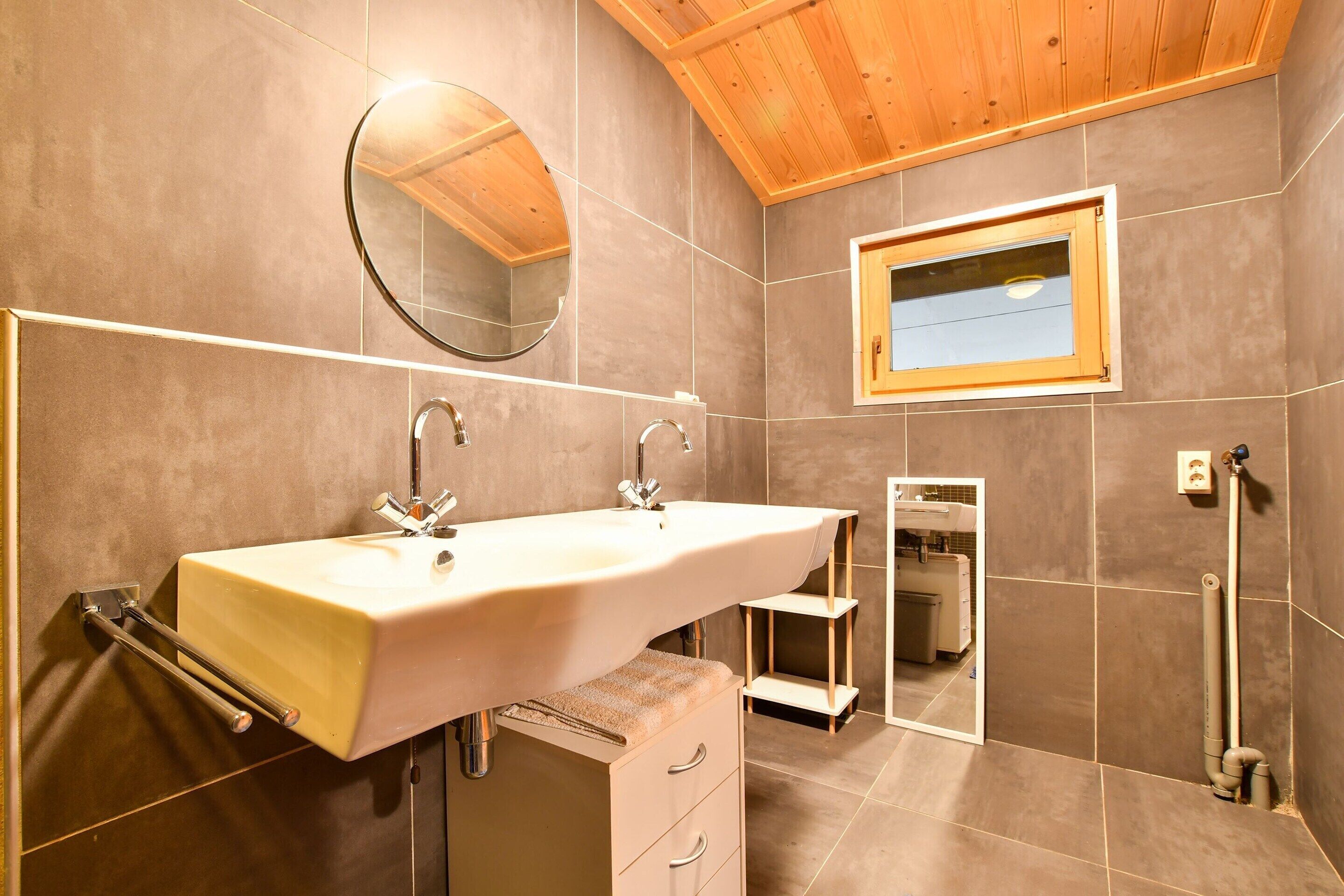 Un bagno moderno con doppio lavabo, un grande specchio e un soffitto in legno.