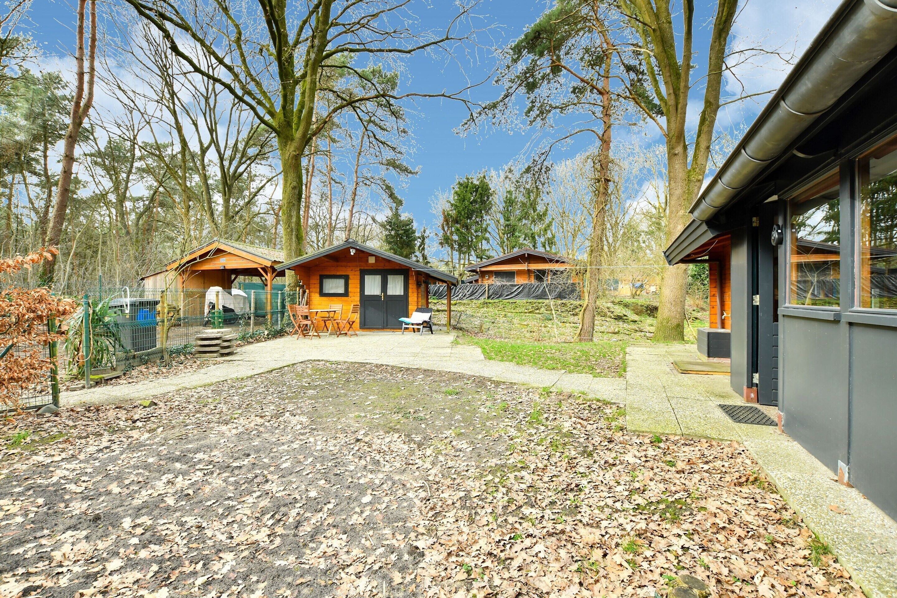 A cabin-style building with a wooden exterior, a fenced outdoor area with a table and chairs, and a clear sky.