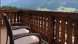 A wooden deck with two wicker chairs, a wooden railing, and a mountain view. - Affluent Chalet in Neukirchen near Wildkogel Ski Arena (Neukirchen am Grossvenediger)