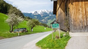 Une route de campagne bordée d’un bâtiment en bois et d’un panneau indiquant « Ferienwohnungen Geisler Dörfli 344 ».