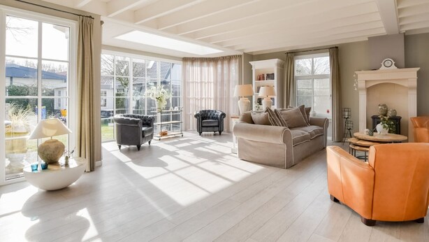 A spacious living room with a large window, a fireplace, and a cozy seating area. - Great Holiday Home at the Efteling with Heated Swimming Pool & Hot Tub (Kaatsheuvel)