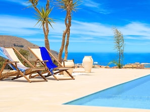 Un espace aménagé au bord de la piscine, avec des chaises longues et un grand vase.