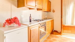 A kitchen with wooden cabinets, a white countertop, a stove, and an oven. - Pet-friendly Space With Pool (Gambassi Terme)