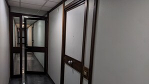 Un couloir avec une porte en bois et un panneau de verre.