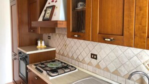 A kitchen with wooden cabinets, a gas stove, and a tiled backsplash. - Belvilla by OYO Tenute D'angelo (Agrigento)
