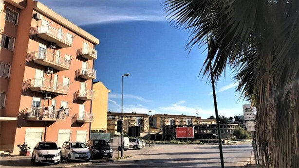 A multi-story residential building with balconies, parked cars, and a clear blue sky. - Belvilla by OYO Tenute D'angelo (Agrigento)