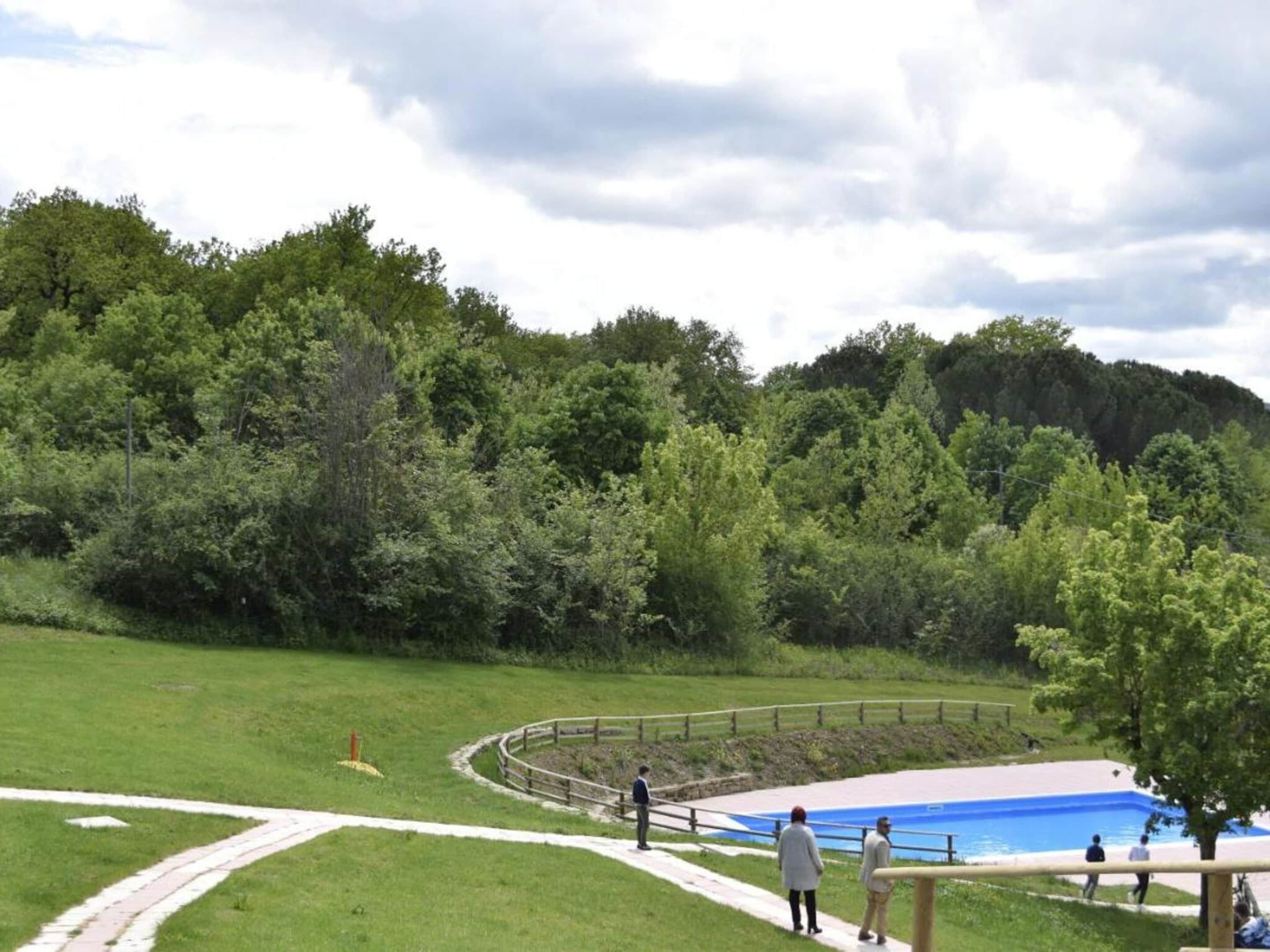 Un parc doté d’une piscine, de pelouses et d’une clôture en bois.