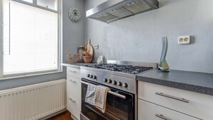 Une cuisine équipée d’une cuisinière, d’un four et d’une fenêtre avec des stores.