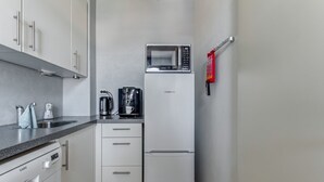 Une cuisine compacte équipée d’un four à micro-ondes, d’une machine à café et d’un réfrigérateur.