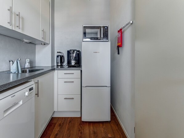 A compact kitchen with a microwave, coffee maker, and a refrigerator.