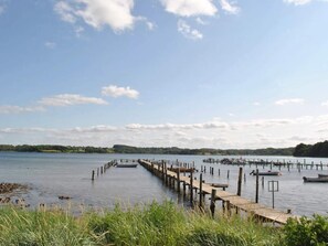 A calm lake with wooden docks extending into the water, surrounded by greenery and a clear sky.