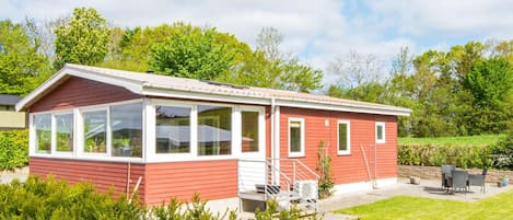 A red single-story building with a covered porch, a staircase, and a patio area with outdoor furniture.