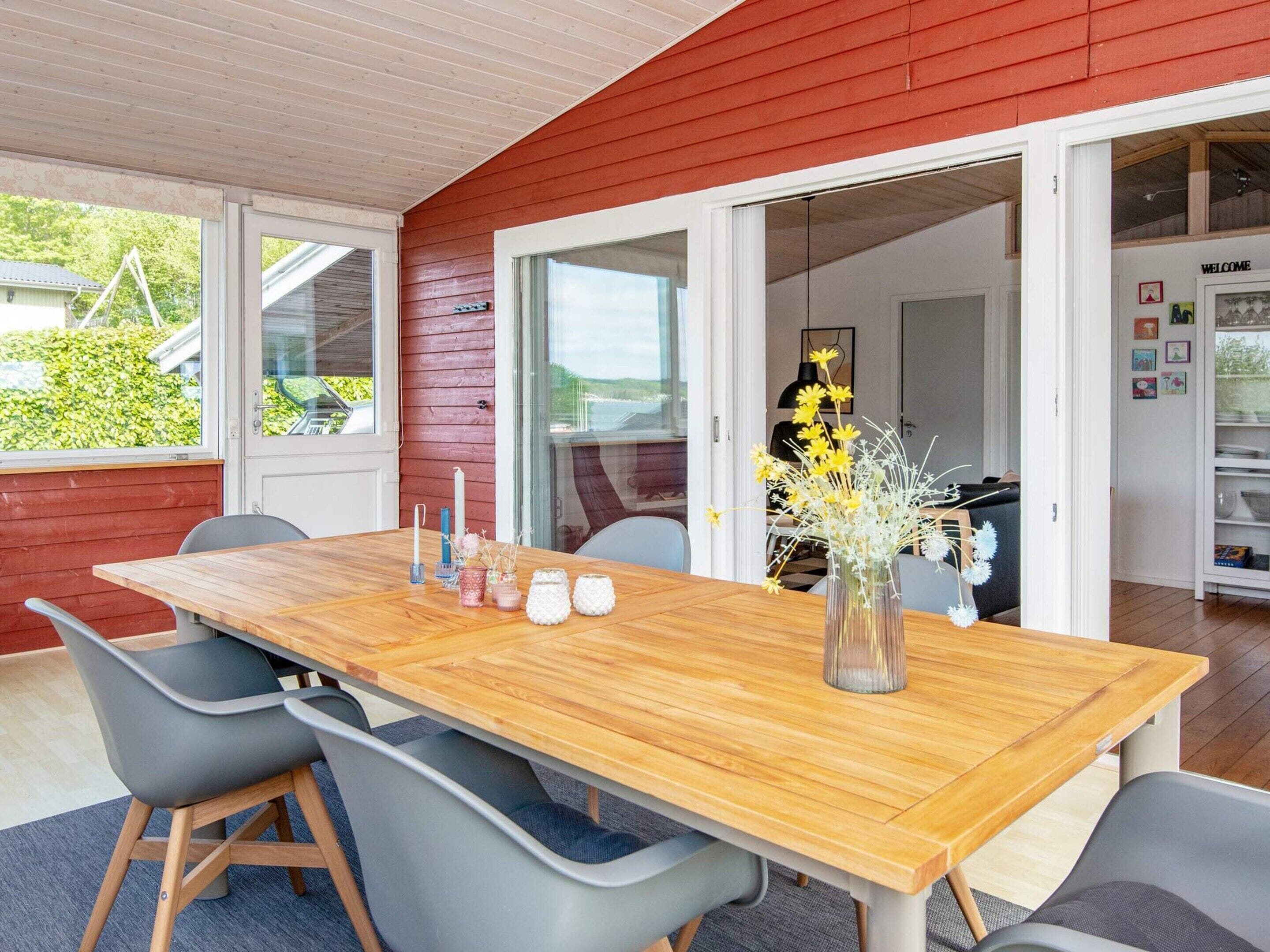 A dining area with a wooden table, grey chairs, and a vase with flowers.