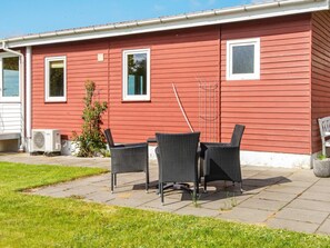 A red house with two windows, a patio with chairs, and a small garden. - 4 Person Holiday Home in Haderslev (Haderslev)