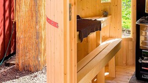 A wooden sauna room with a bench, a small window, and a sauna heater. - 4 Person Holiday Home in Tibro (Tibro)