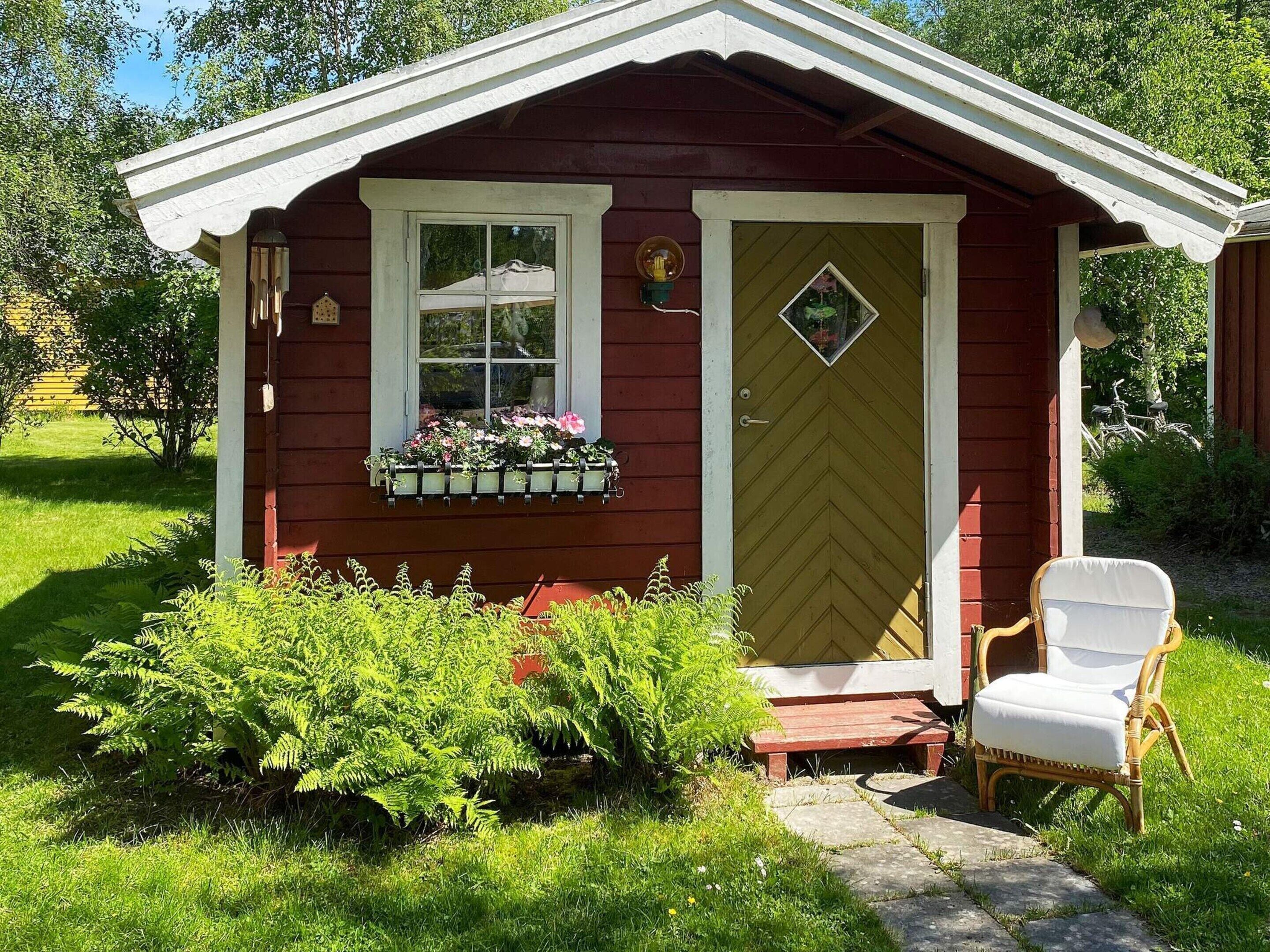 A small wooden structure with a door, a window, and a bench outside.