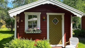 A small wooden structure with a door, a window, and a bench outside. - 4 Person Holiday Home in Tibro (Tibro)