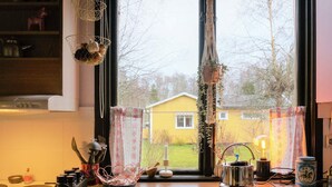 A kitchen with a window, a yellow house outside, and various kitchen items on the counter. - 4 Person Holiday Home in Tibro (Tibro)